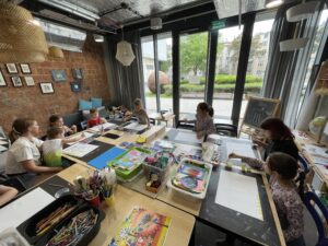 Warsztaty plastyczne i arteterapia dla dzieci – zajęcia rozwojowe przy dużym stole, kreatywna przestrzeń i dzieci w trakcie pracy